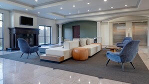 A spacious living area with a fireplace, a sofa set, and two armchairs. - Wyndham Lake Charles (Lake Charles)