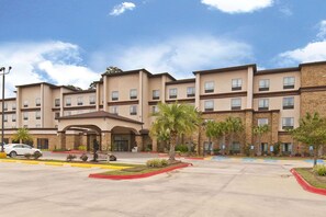 Welcome to our hotel, featuring a central entrance with a covered walkway and landscaped areas with palm trees.