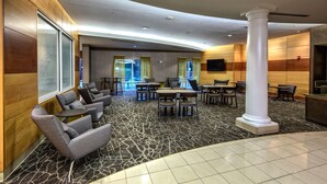 A modern hotel lobby with a mix of seating areas, a large pillar, and a flat-screen TV mounted on the wall. - Springhill Suites by Marriott New Bern (New Bern)