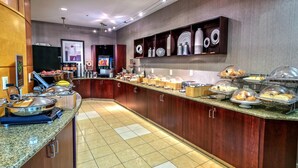 A buffet setup with various food items and serving utensils. - Springhill Suites by Marriott New Bern (New Bern)