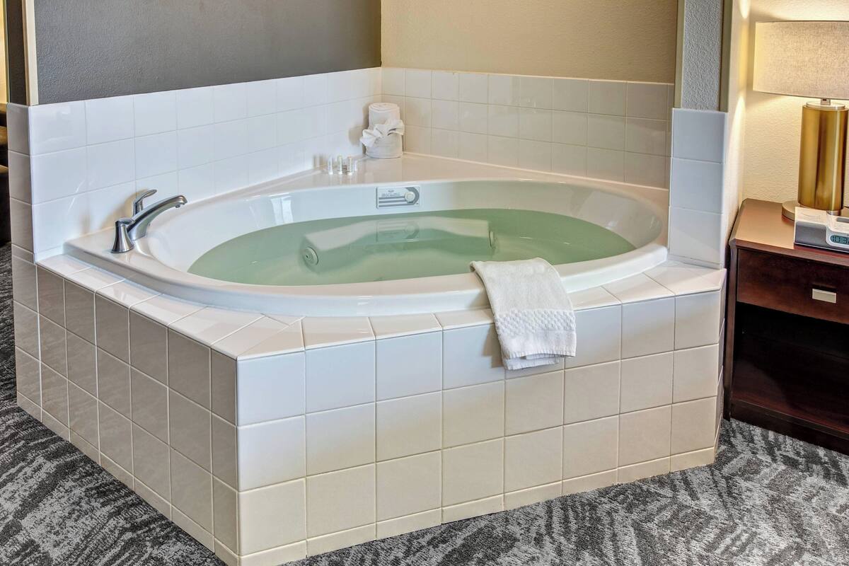 Um banheiro moderno com uma banheira de pé, um porta-toalhas e uma pequena mesa de cabeceira com abajur.