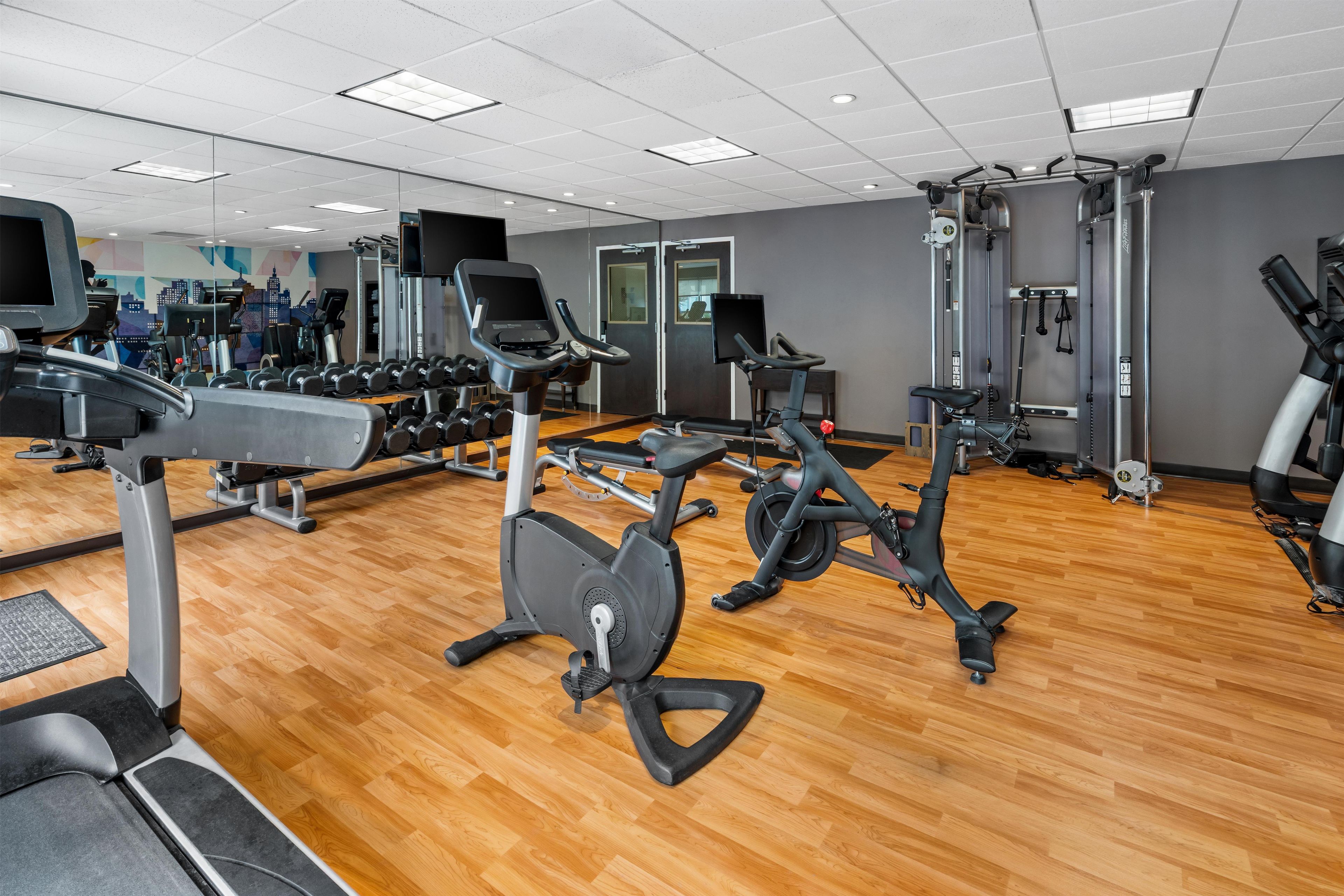 Et fitnesscenter med forskellig træningsudstyr, herunder løbebånd, motionscykler og styrkemaskiner.
