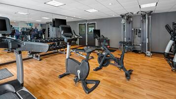 Et fitnesscenter med forskellig træningsudstyr, herunder løbebånd, motionscykler og styrkemaskiner.