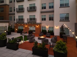 A courtyard with outdoor seating, a fire pit, and string lights.