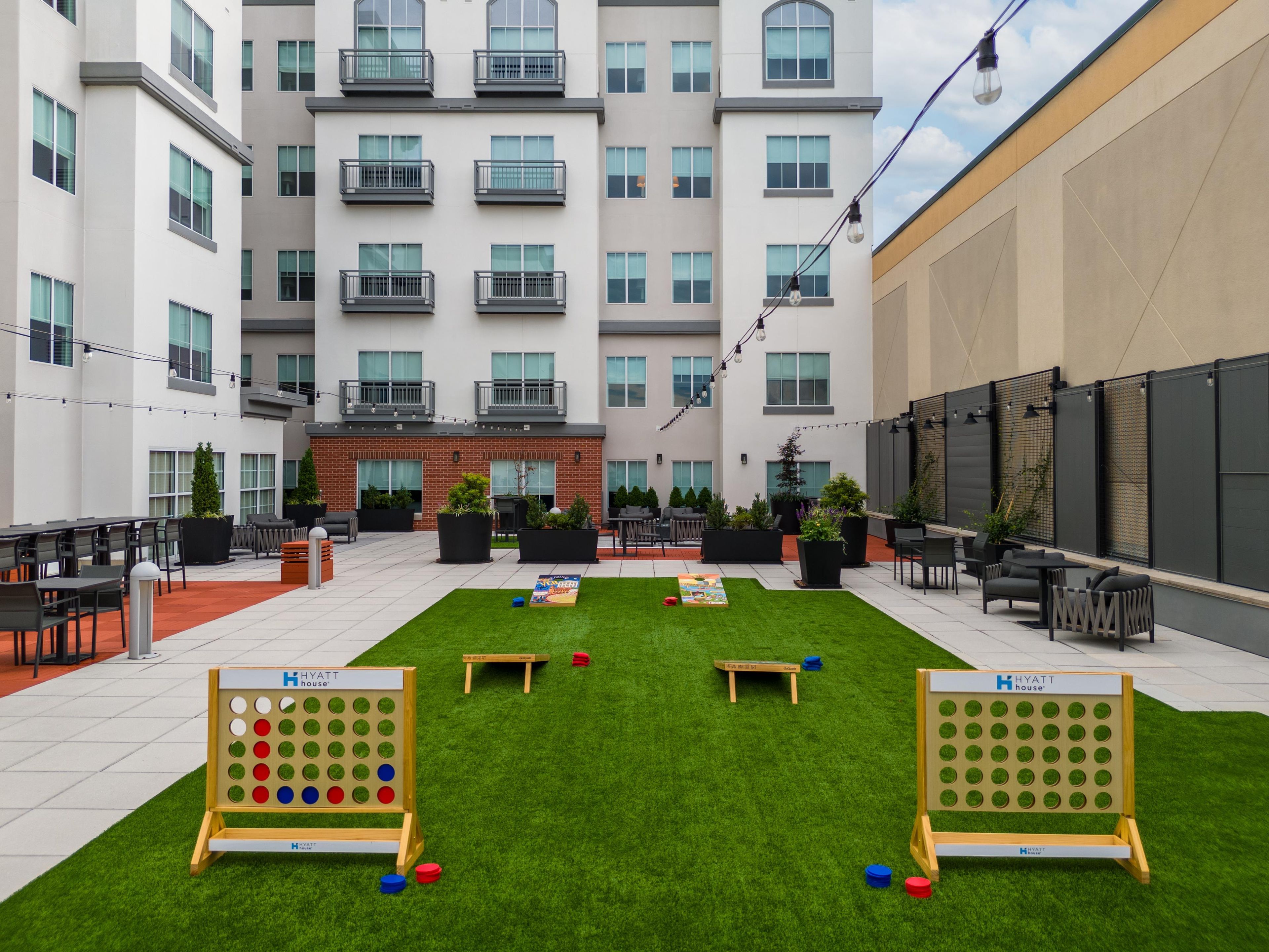 A courtyard with outdoor seating, a lawn game setup, and a building with multiple balconies.
