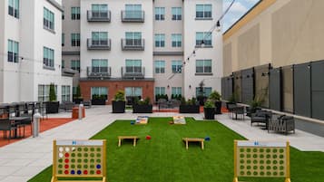 A courtyard with outdoor seating, a lawn game setup, and a building with multiple balconies.