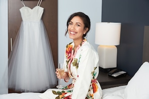Une chambre d’hôtel avec un lit, une lampe de chevet, un téléphone et une robe accrochée au mur.