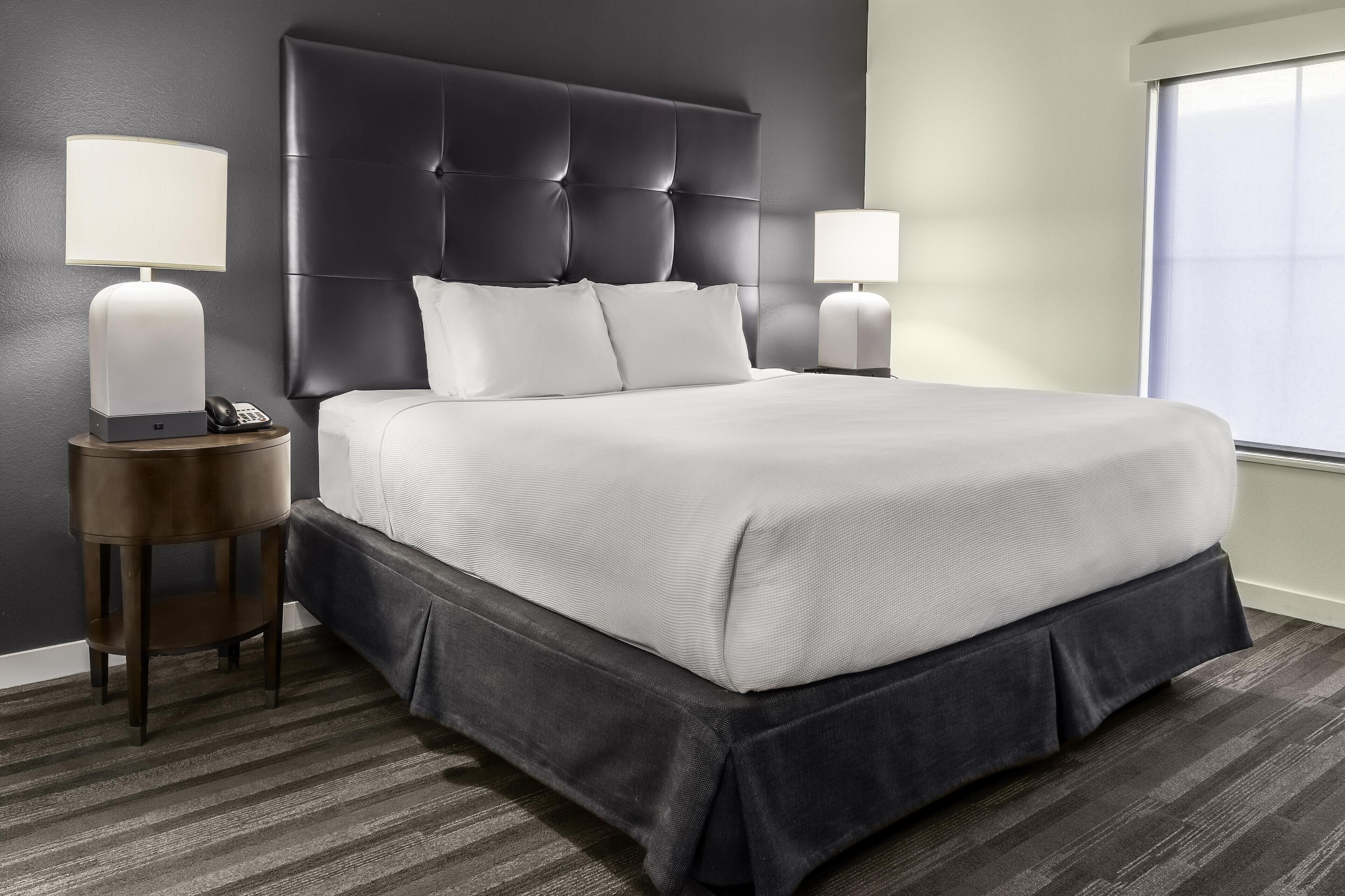 A hotel room with a large bed, two bedside tables, and a window.