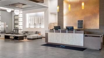 A modern reception area with a marble counter, seating, and a large wall-mounted artwork.