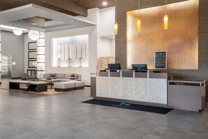 A modern reception area with a marble counter, seating, and a large wall-mounted artwork.
