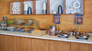A breakfast buffet with various food items, including fruits, pastries, and a coffee machine. - SpringHill Suites by Marriott Saginaw (Saginaw)