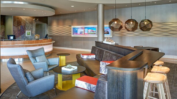 A modern lobby with a reception desk, seating area, and a large column. - SpringHill Suites by Marriott Saginaw (Saginaw)