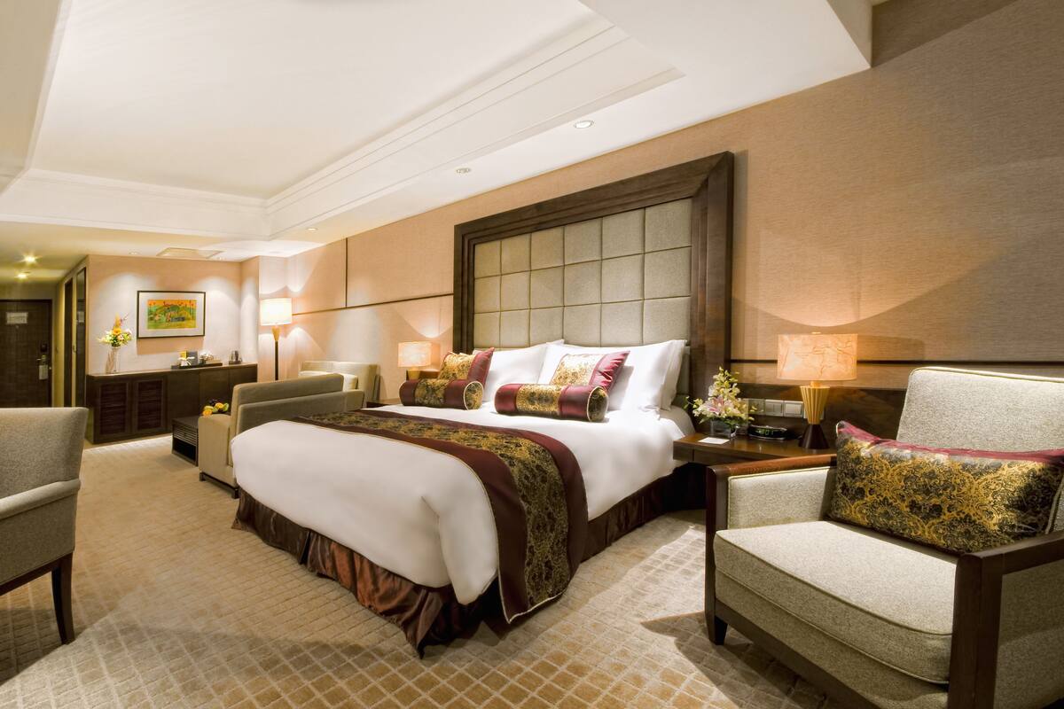 Une chambre d’hôtel avec un grand lit, deux tables de chevet, une chaise, un bureau et une lampe.
