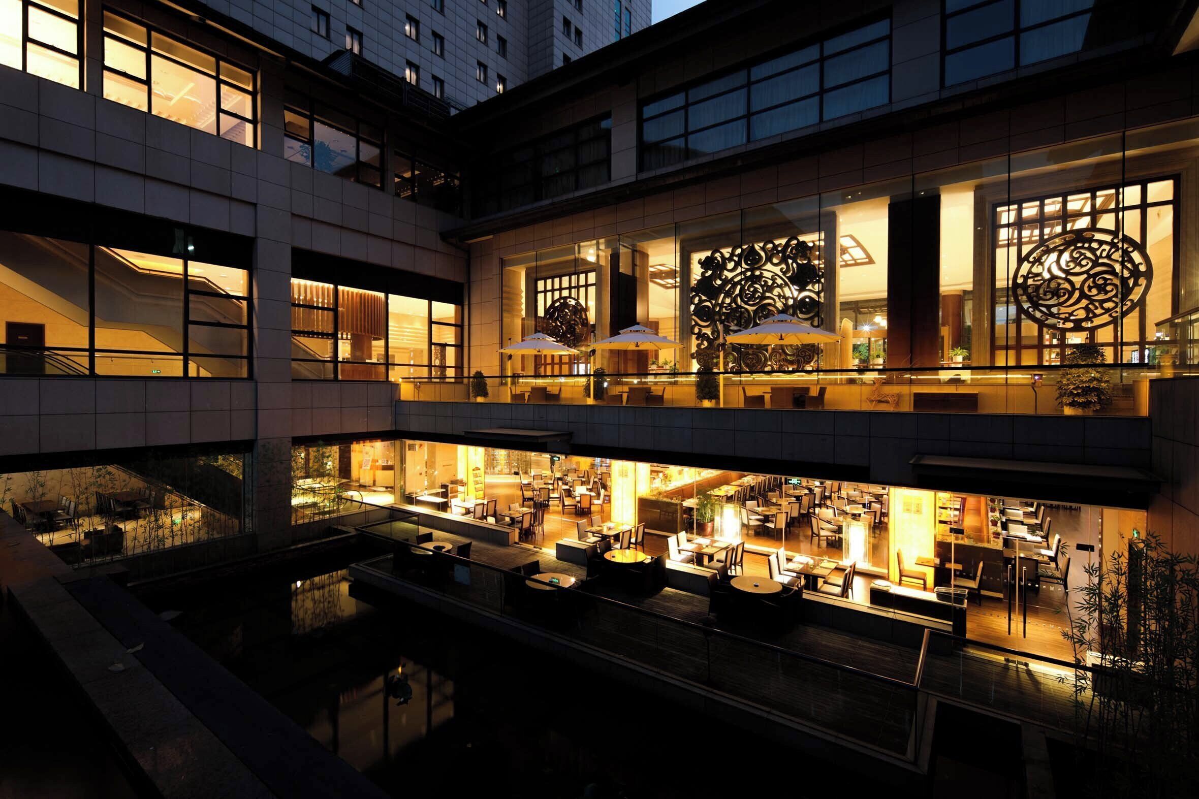 A multi-story hotel with a spacious lobby, outdoor seating area, and a view of the surrounding buildings.
