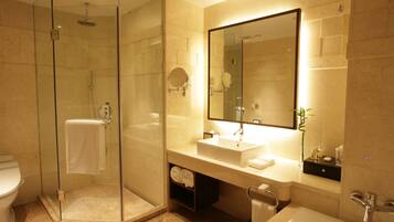 A modern bathroom with a glass-enclosed shower, a large mirror, and a white sink.