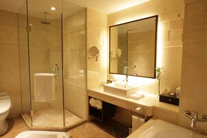 A modern bathroom with a glass-enclosed shower, a large mirror, and a white sink.