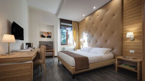 A modern hotel room with a large bed, a desk, a chair, a television, and a window with curtains. - Phi Hotel Garden Area Roma Eur (Rome)