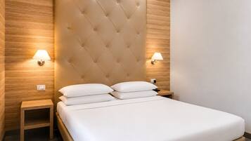 A hotel room with a tufted headboard, two bedside lamps, a wooden nightstand, and a bed with white bedding.