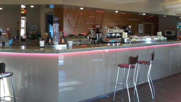 Zona de bar moderna con una barra curva, taburetes y una máquina de café.