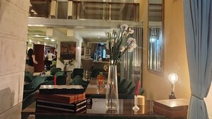 Un hall d’hôtel moderne comprenant un espace salon, une table à manger et un vase décoratif avec des fleurs.