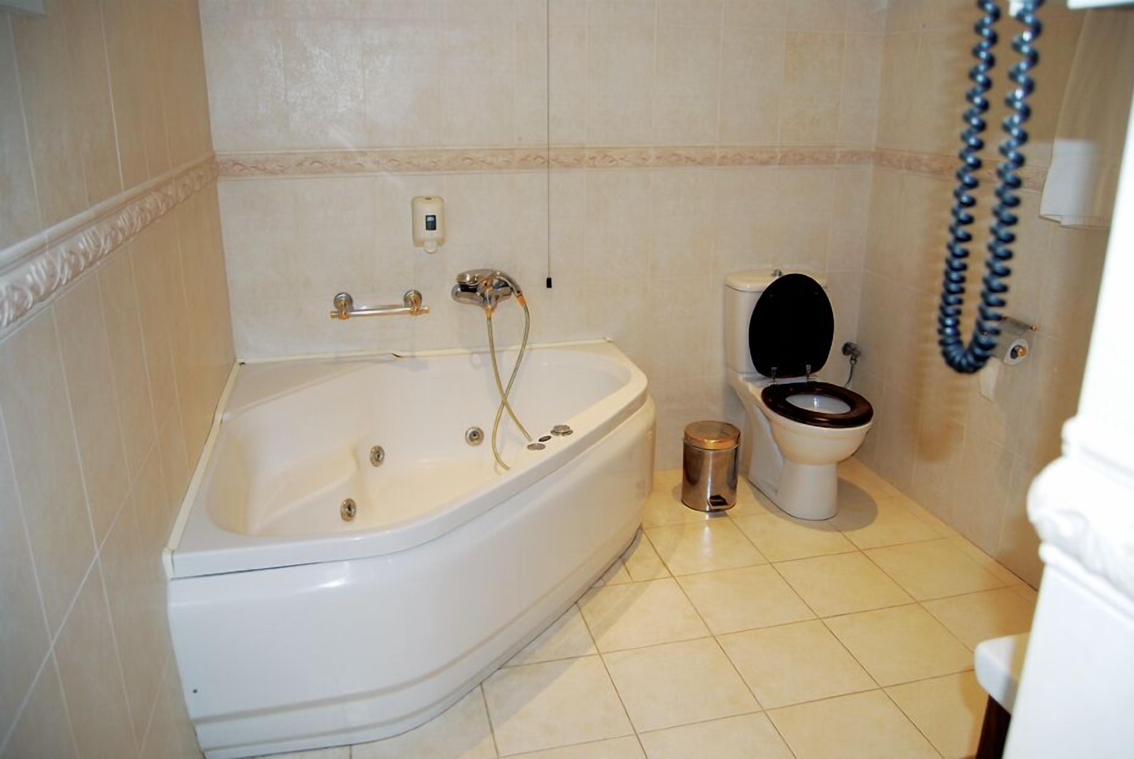 A bathroom with a bathtub, toilet, and a hand dryer.