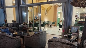 Un hall d’entrée spacieux, agrémenté de meubles en osier, d’un coin repas et d’un lustre.
