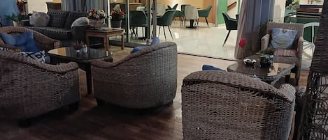 A spacious lobby with wicker furniture, a dining area, and a chandelier.