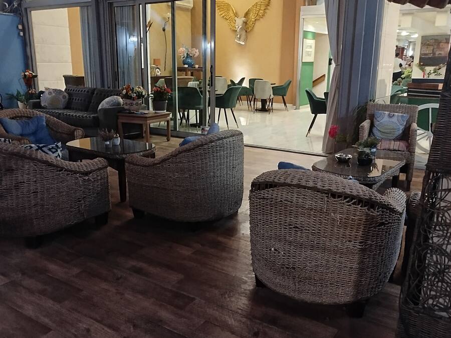 Un vestíbul ampli amb mobles de vimet, una zona de dinar i un penjallum.