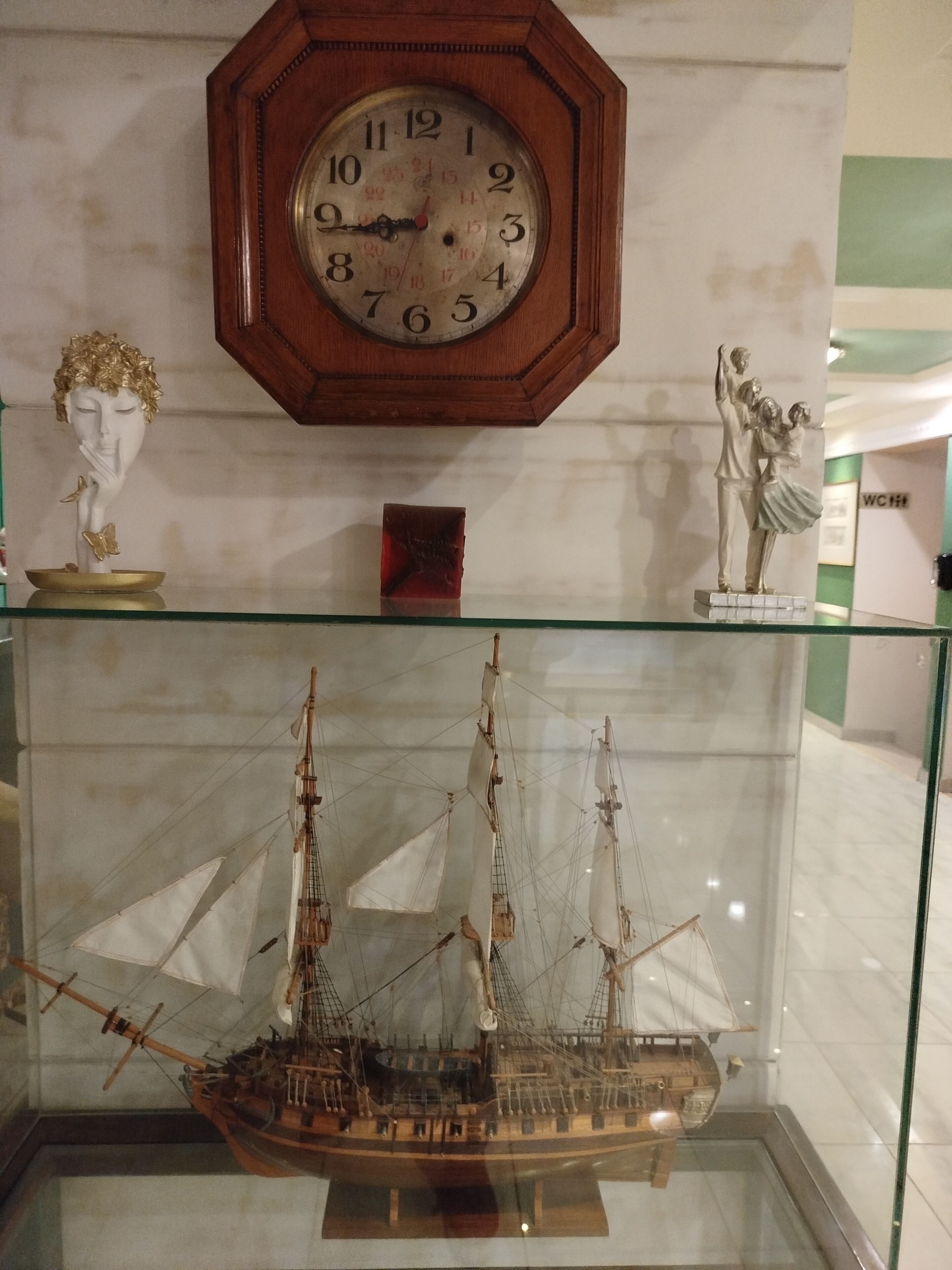 Une horloge, un buste, une statue et une maquette de navire.