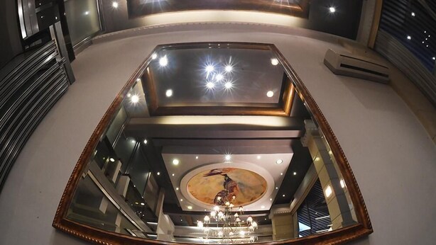 Un vaste atrium doté d’un lustre central, d’un plafond décoratif et d’un grand miroir qui reflète l’espace.