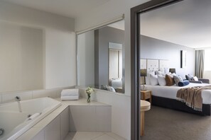 A modern bathroom with a bathtub, a mirror, and a sink. - Fable Christchurch (Christchurch)