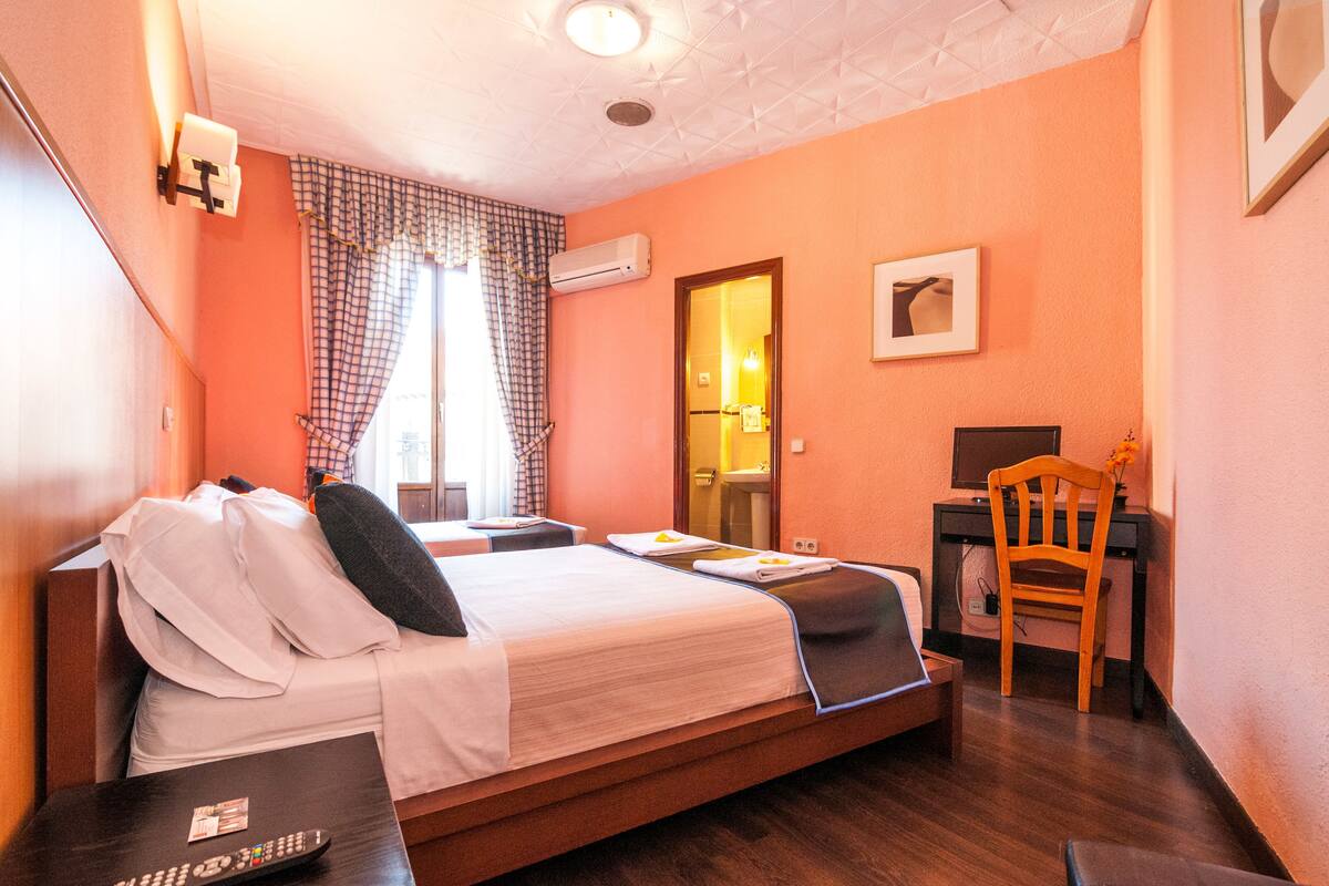 A hotel room with a bed, a desk, a chair, and a bathroom door.