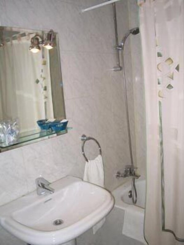 A bathroom with a sink, mirror, shower, and towel rack.