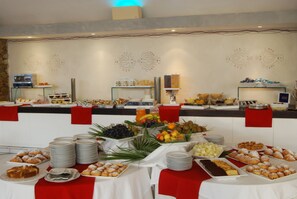 A buffet with various food items and a decorative wall with abstract designs.