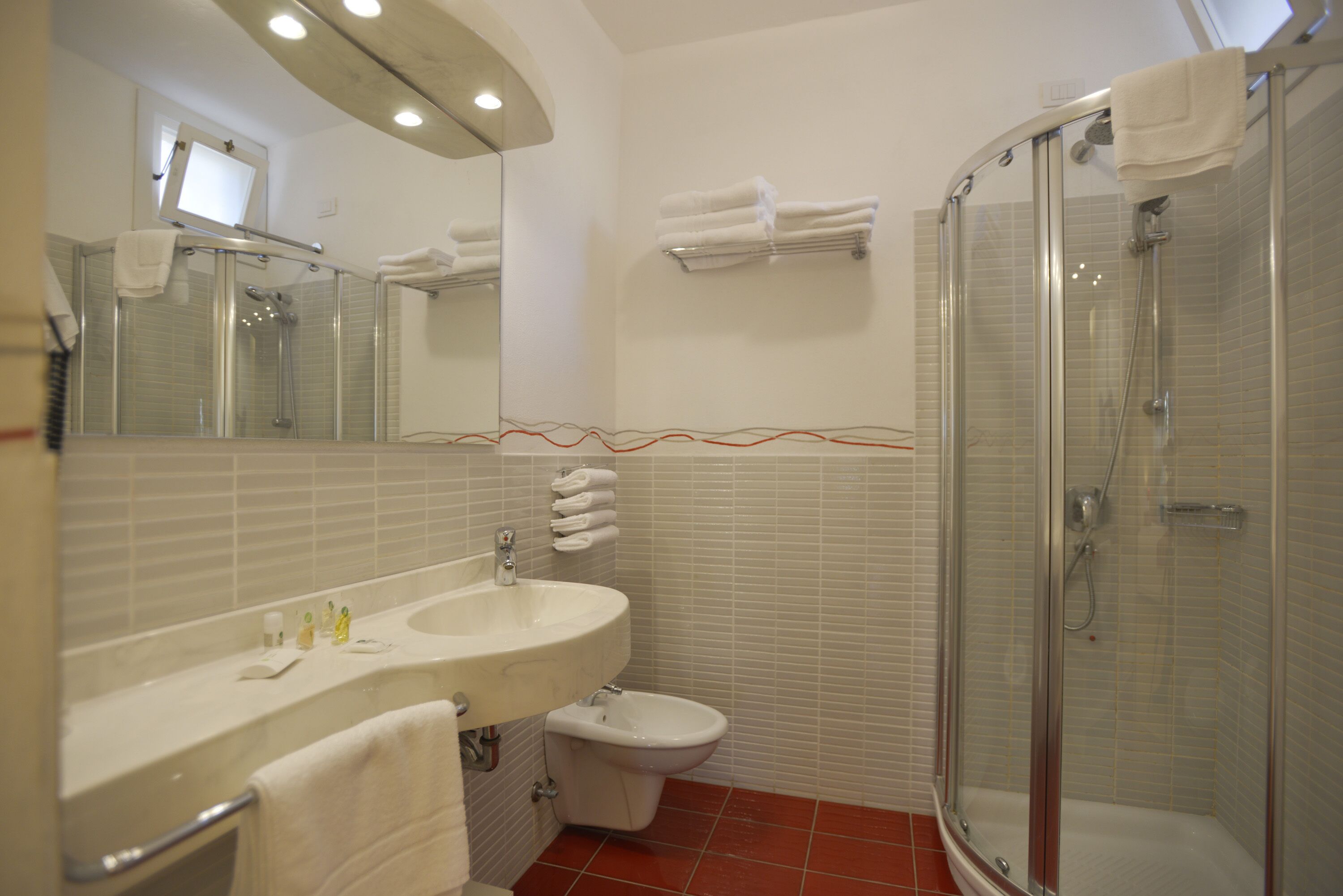 A modern bathroom with a glass-enclosed shower, a sink with a mirror, and a toilet.