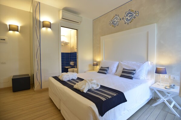 A hotel room with a large bed, bedside lamps, a small table, and a mirror.