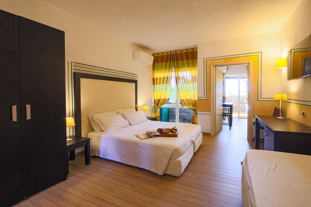 A hotel room with a bed, bedside table, and a desk with a chair.