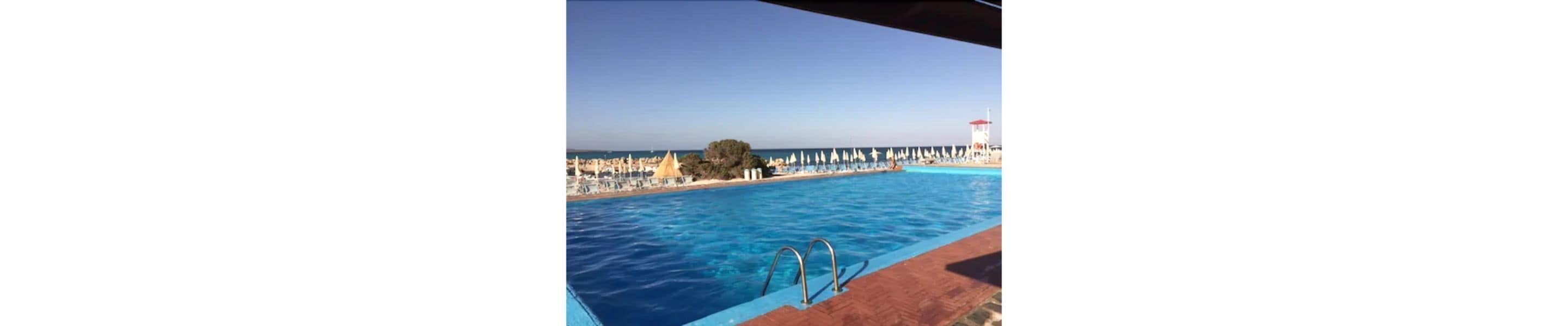 A swimming pool with a view of the sea and beach umbrellas.