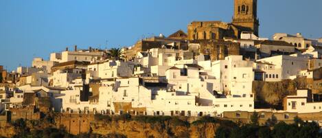 A densely packed hillside town with white buildings and a prominent tower.