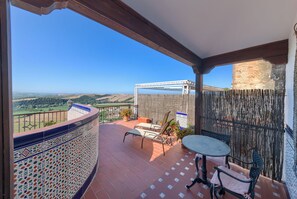 A balcony with a tiled floor, a table, two chairs, and a pergola. - Hotel El Convento (Arcos de la Frontera)