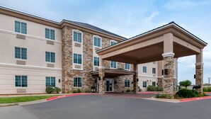 A multi-story hotel with a stone facade, a covered entrance, and a parking lot. - Comfort Inn & Suites, Odessa I-20 (Odessa)