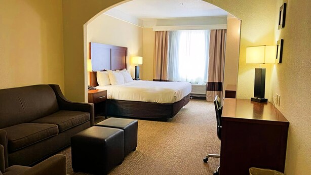 A hotel room with a bed, a sofa, a desk, and a lamp. - Comfort Inn & Suites, Odessa I-20 (Odessa)