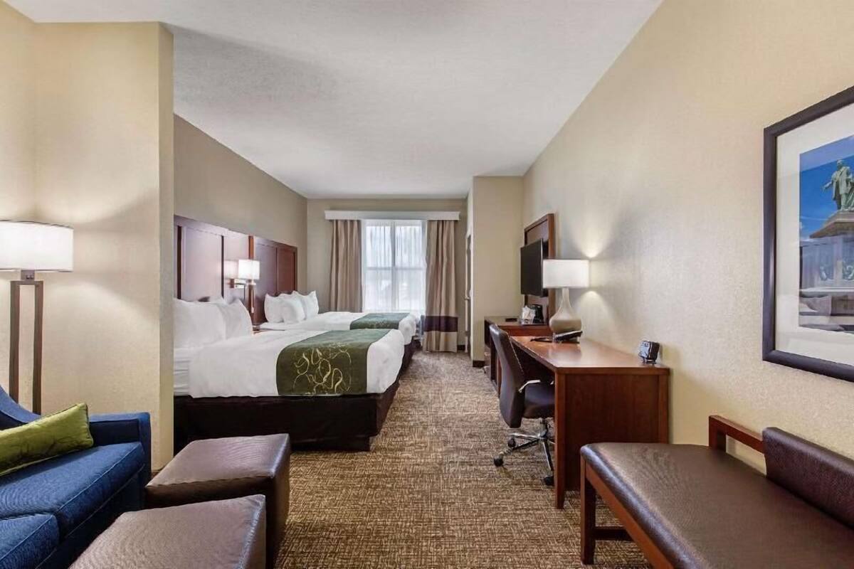 Een hotelkamer met een bed, twee nachtkastjes, een bureau, een stoel en een bank.