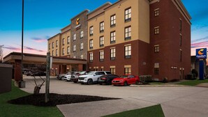 Een Comfort Suites hotel met een bakstenen gevel, meerdere parkeerplaatsen en een heldere lucht.