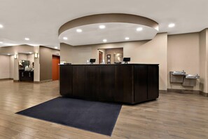A hotel reception area with a dark reception desk, a clock, and a small seating area. - Comfort Suites Nashville near Percy Priest Lake (Nashville)