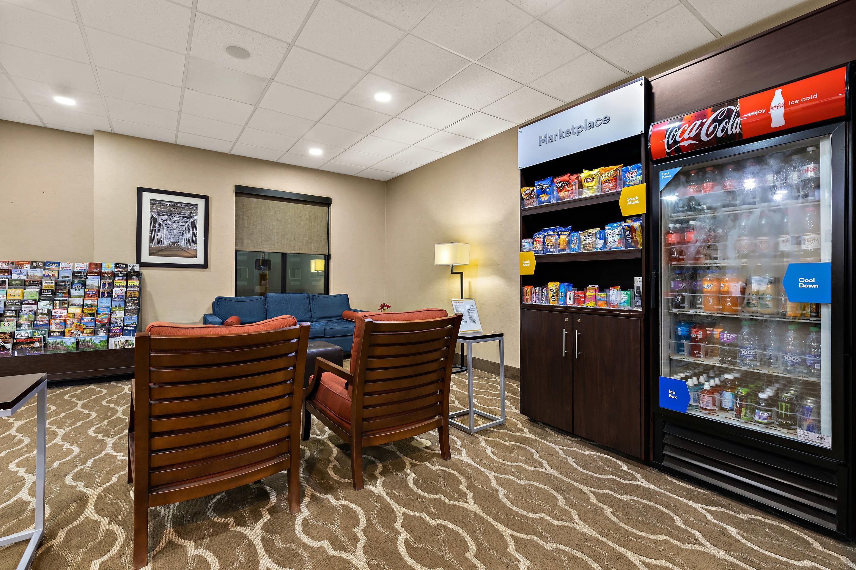 A hotel room with a seating area, a snack bar, and a Coca-Cola refrigerator.