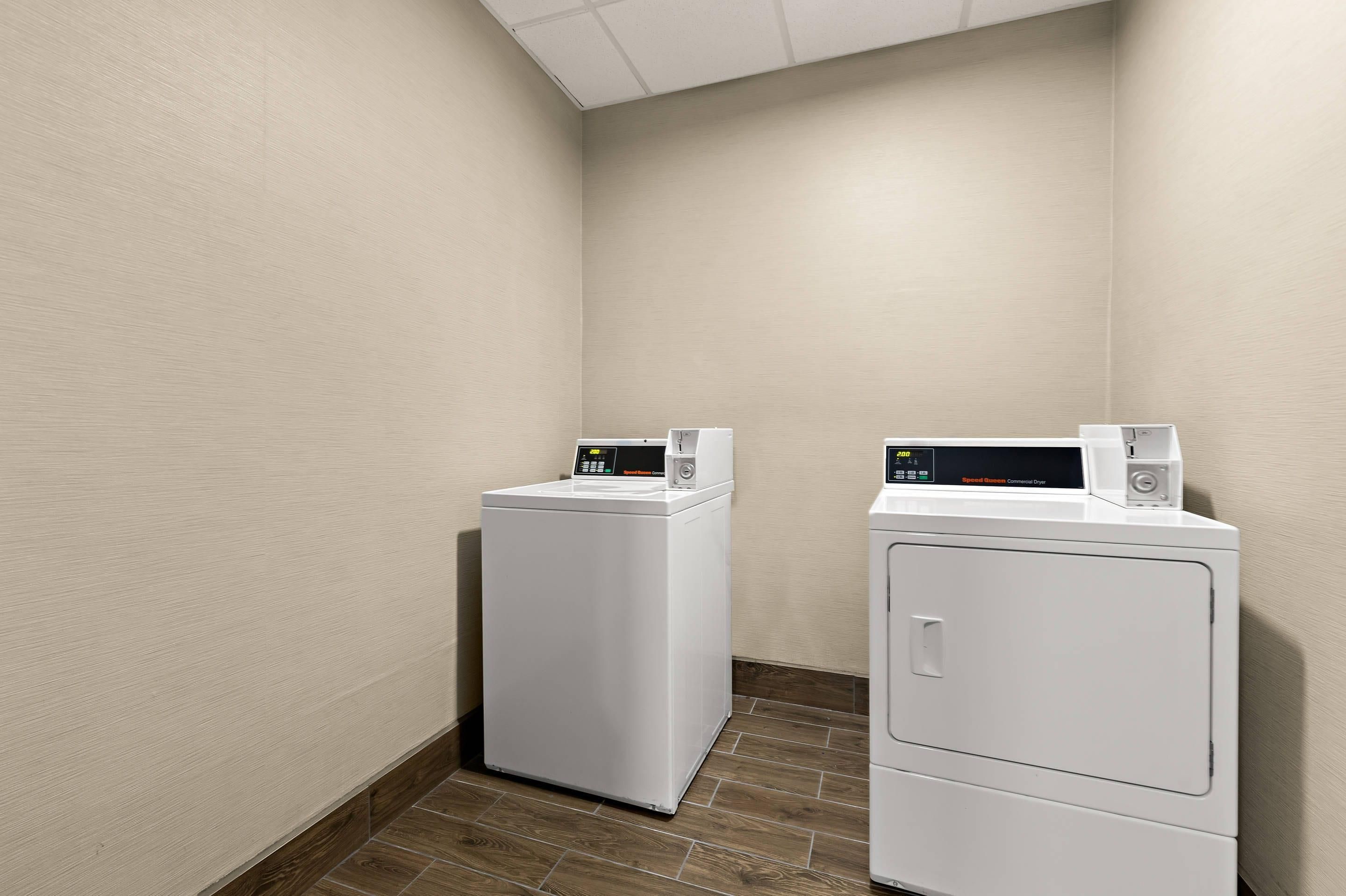A laundry room with two white front-loading washing machines and a dryer.