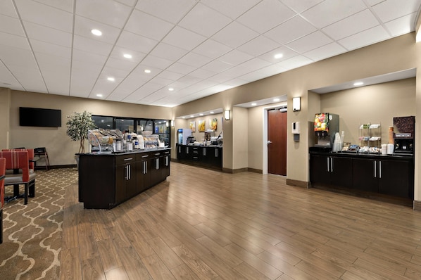 Un amplio vestíbulo de hotel con mostrador de recepción, zona de estar y una mesa de buffet.
