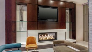 A modern living room with a flat-screen TV, a fireplace, and two sofas. - Fairfield by Marriott New York Manhattan Times Square (New York)