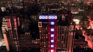 A nighttime cityscape with illuminated buildings and a prominent skyscraper with a distinctive blue and red lighting pattern. - Fairfield by Marriott New York Manhattan Times Square (New York)